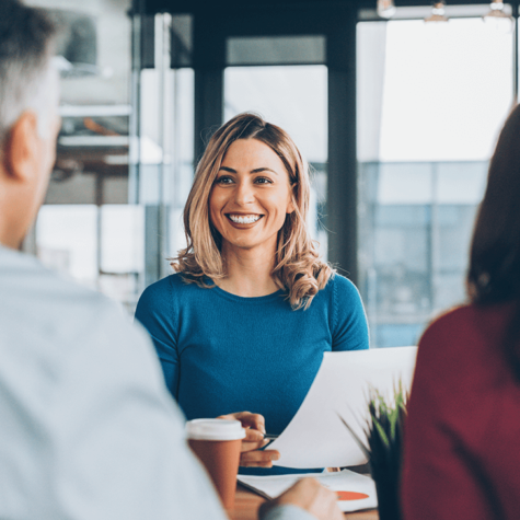 A woman holding a paper and pen smiles at other people seated at a conference room table. Social Security Disability appeals hearings are less formal than courtrooms you might picture, but it’s still crucial to be prepared.